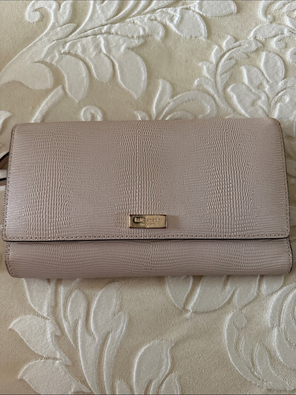 kate spade textured clutch in blush beige with gold logo in good condition.